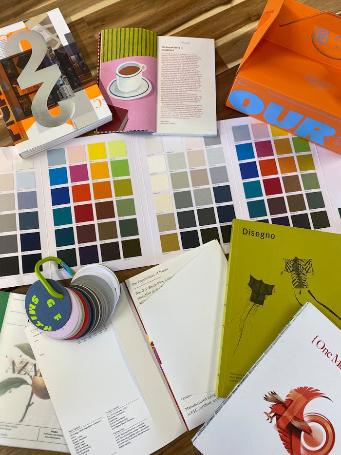 A vibrant arrangement of color swatches and design books placed on a wooden table, perfect for creativity projects.